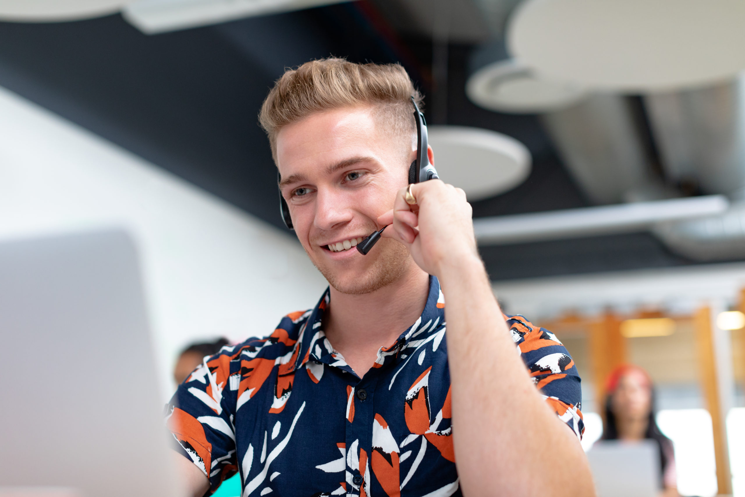 Front view of happy Caucasian male customer service executive talking on headset in a modern office