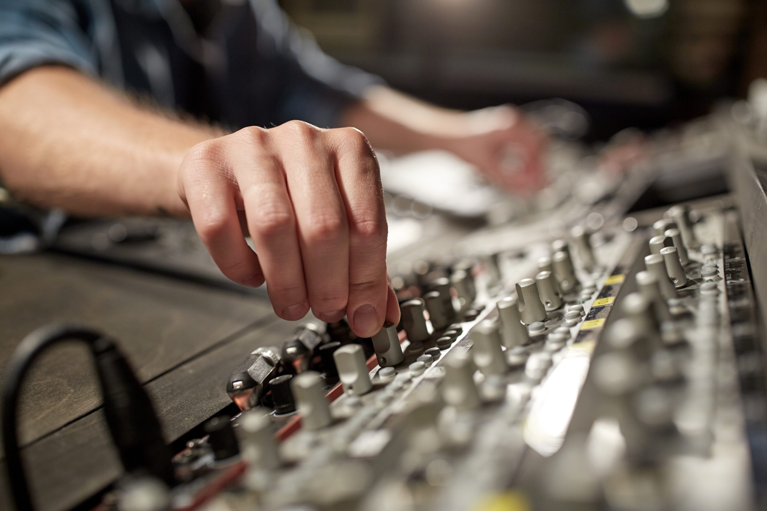 music, technology, people and equipment concept - man using mixing console in sound recording studio