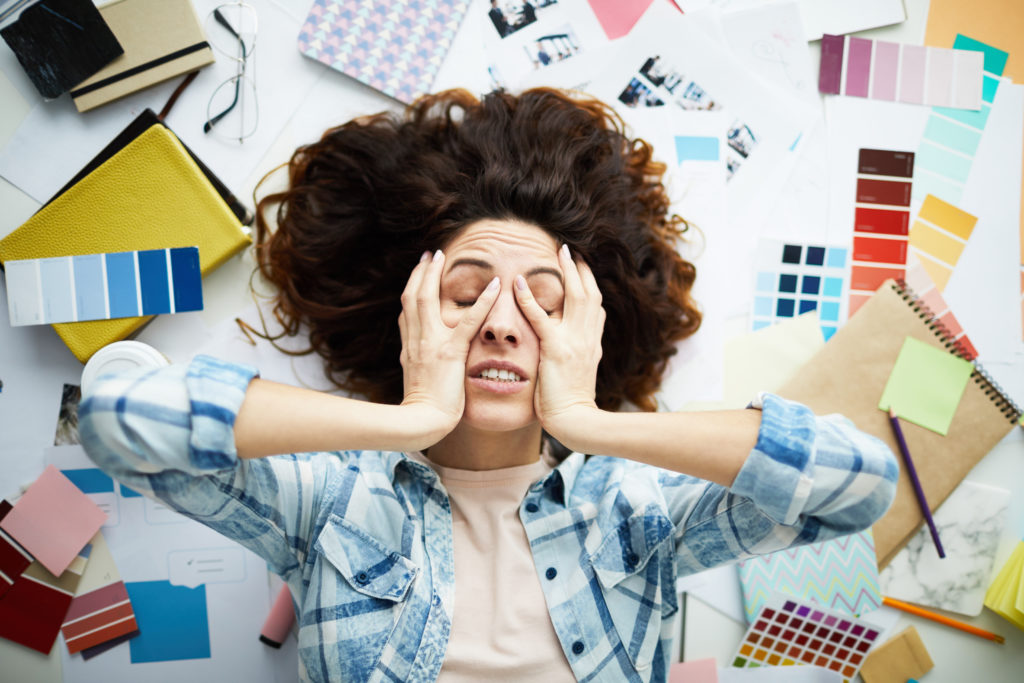 Top view portrait of exhausted designer lying in pile of work with eyes closed, copy space